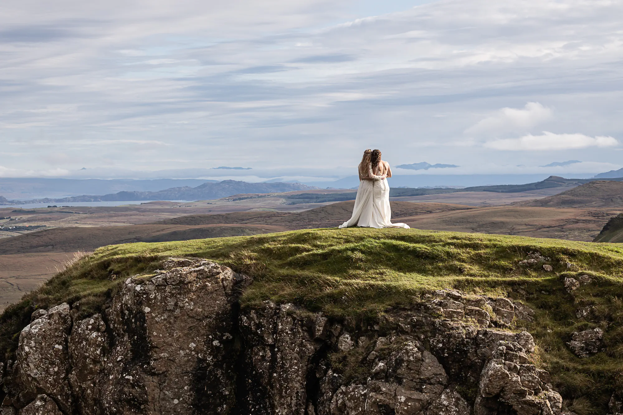 two brides just married embrace on a mountain