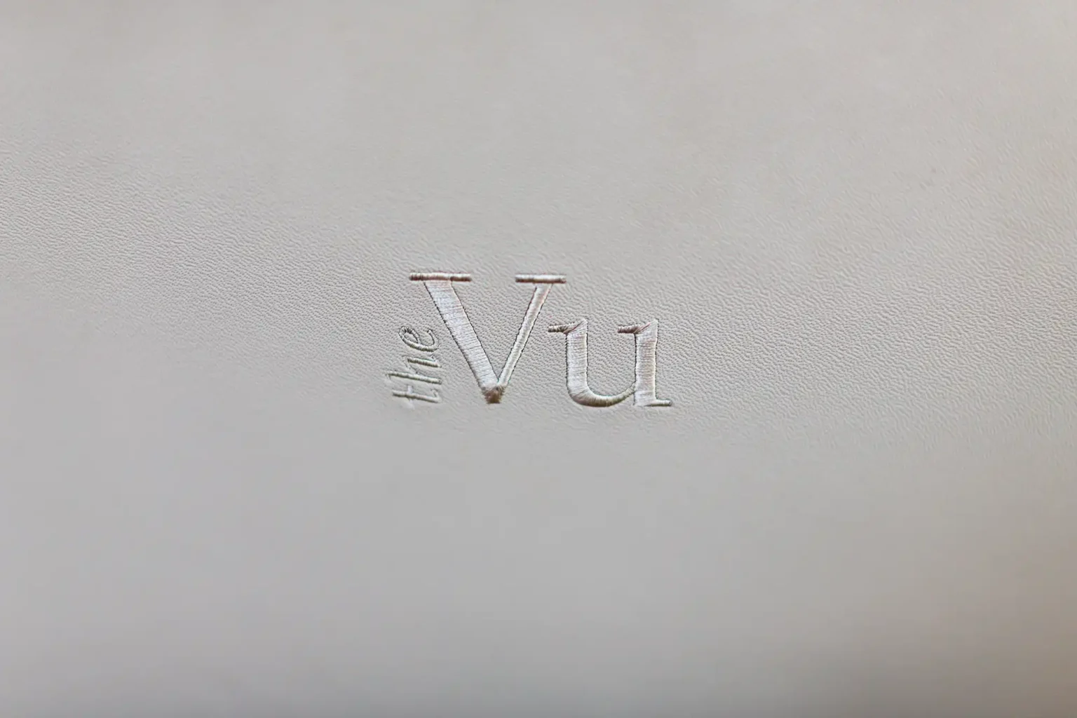 Embossed text "the vu" on a textured white background.