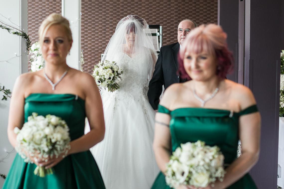 bride and her father follow bridesmaids up the aisle