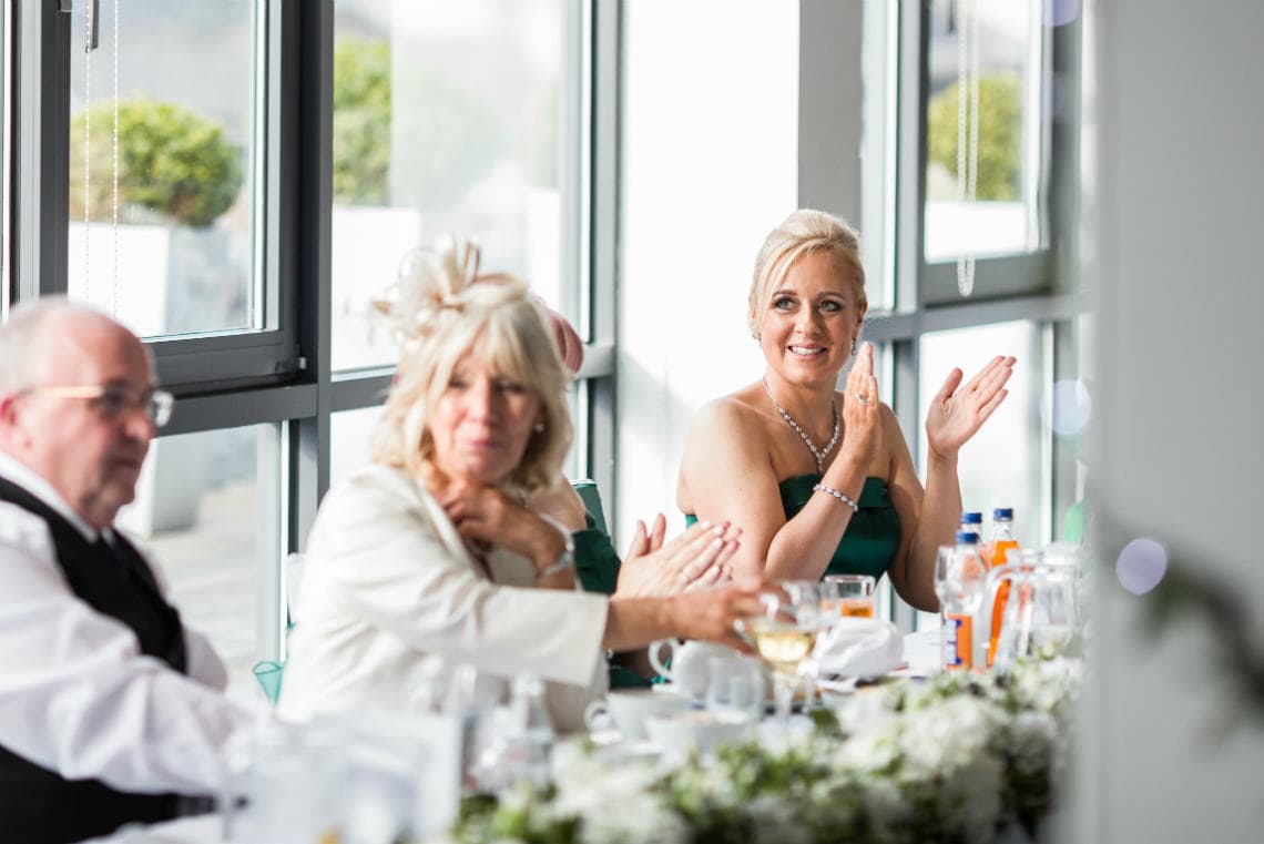 bridesmaid clapping and smiling during groom's speech