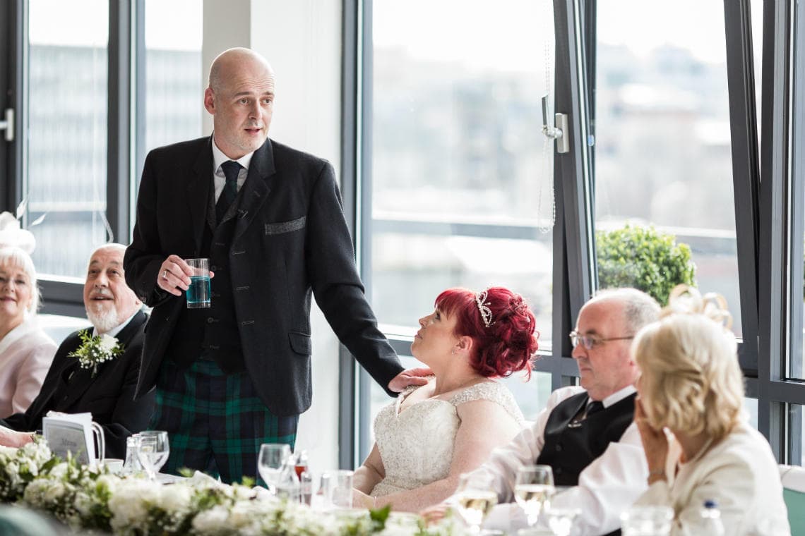 bride looking at groom during his wedding speech