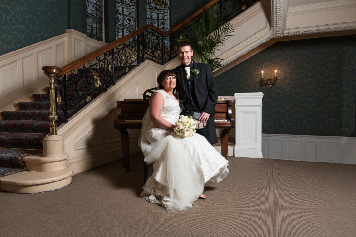 newlyweds in front of the piano at the grand staircase