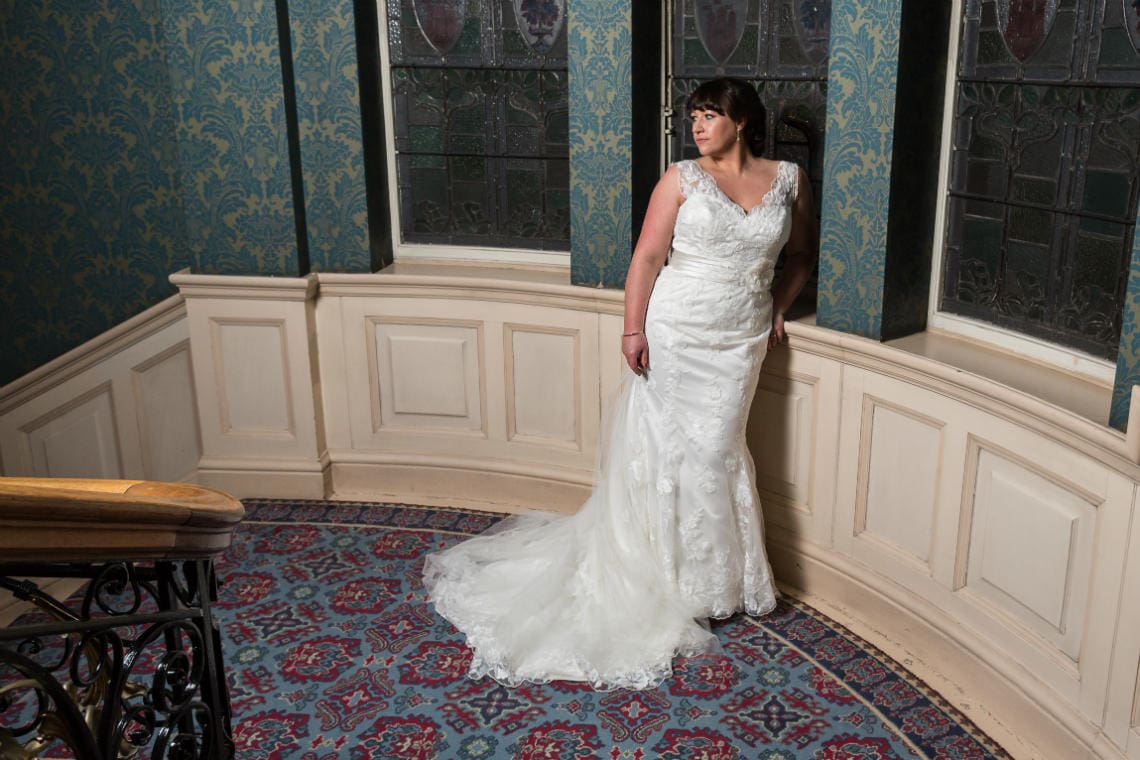 bride standing next to the stained glass window