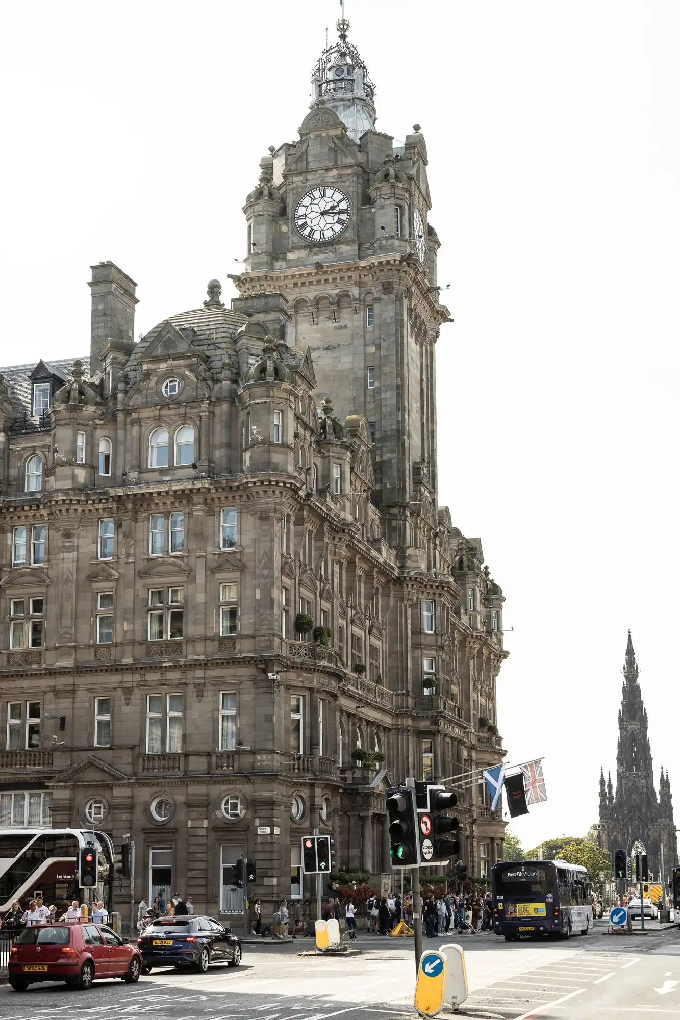 Balmoral Hotel weddings image of a bustling street scene at the base of the hotel in Edinburgh, featuring the hotel's grand clock tower, vehicles, and pedestrians.