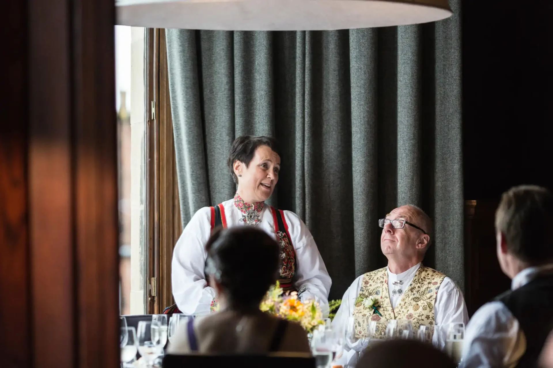 A woman in traditional attire conversing with a man in a similar outfit at a formal dining event.