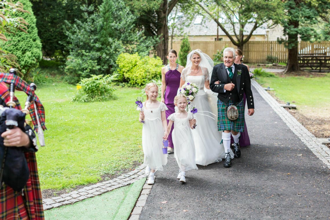 bride, bridesmaids and flowergirls make their way to The Chapel