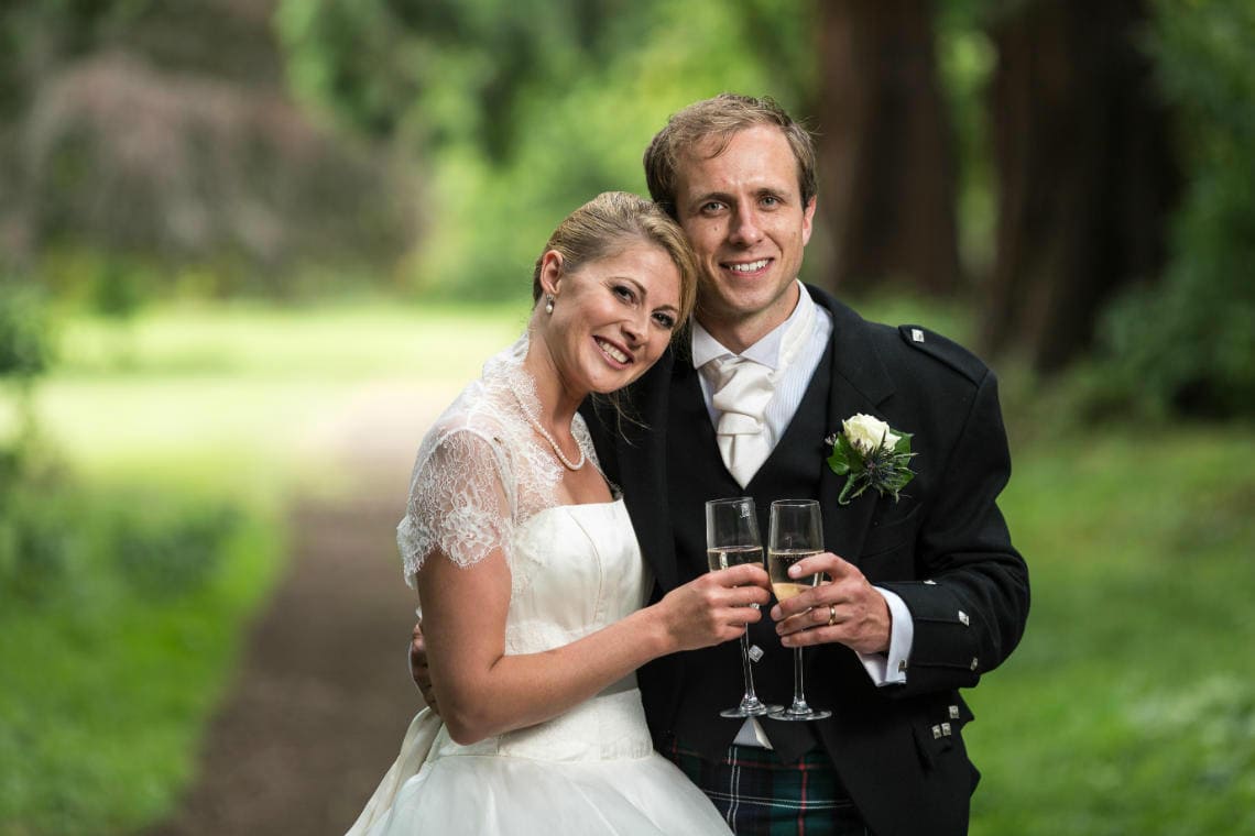 newlyweds raise a toast beneath the giant Redwood trees by Carberry Tower wedding photographer