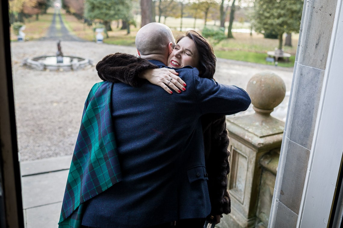 groom is hugged by a friend on the steps