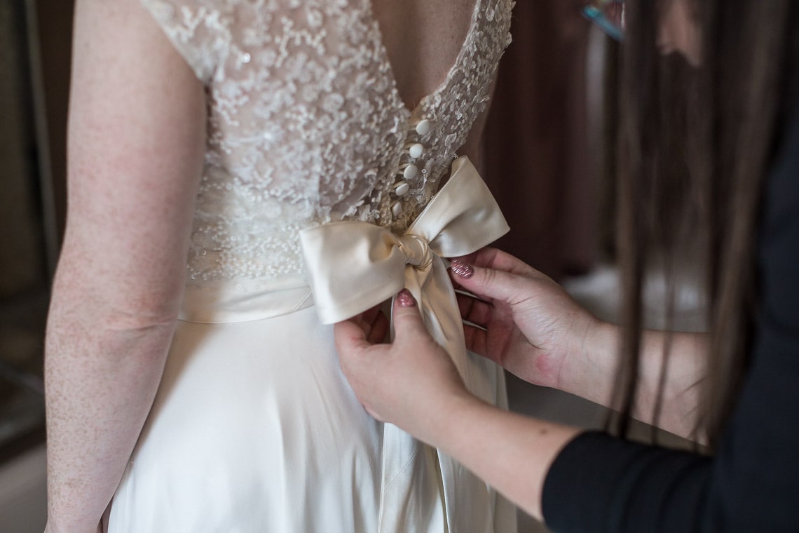 bridal dress last minute adjustment of bow on the back of the dress
