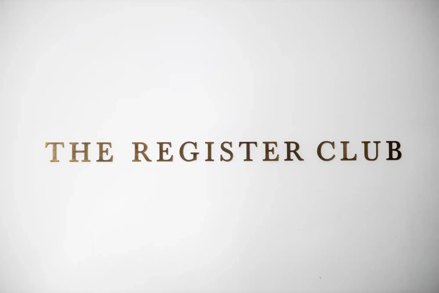 Text reading "the register club" in elegant gold letters on a white background.