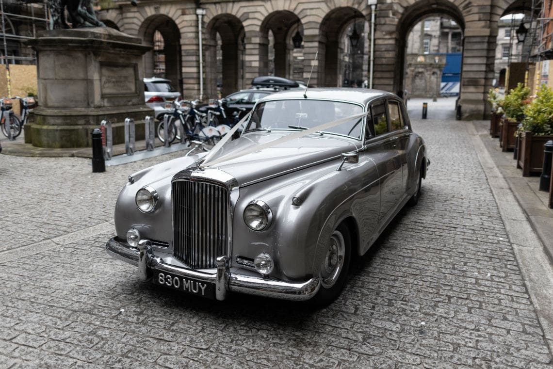 Bride and groom arriving in a classic car for their City Chambers Edinburgh Registry Office wedding