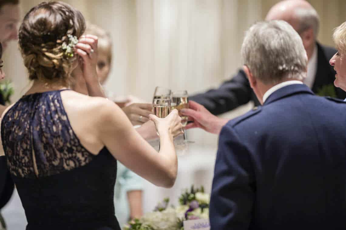 Wedding party raise a glass to toast the happy couple
