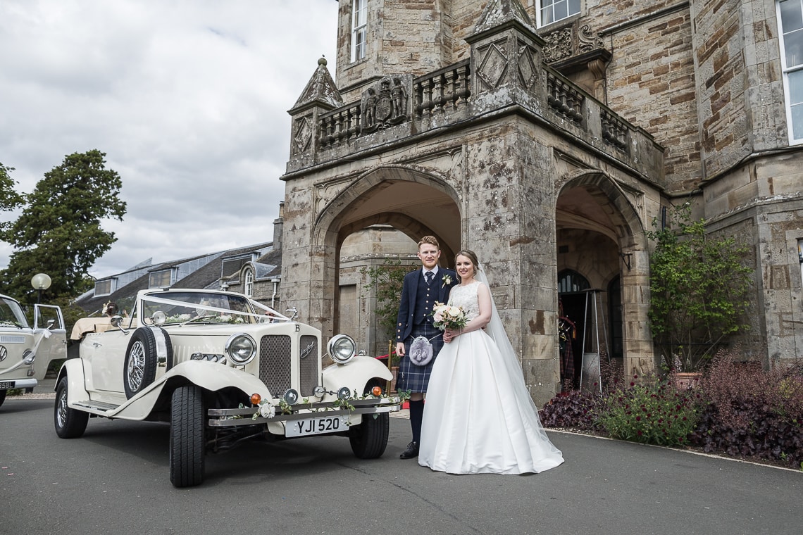 newlyweds standing next to a Beauford card at the hotel entrance