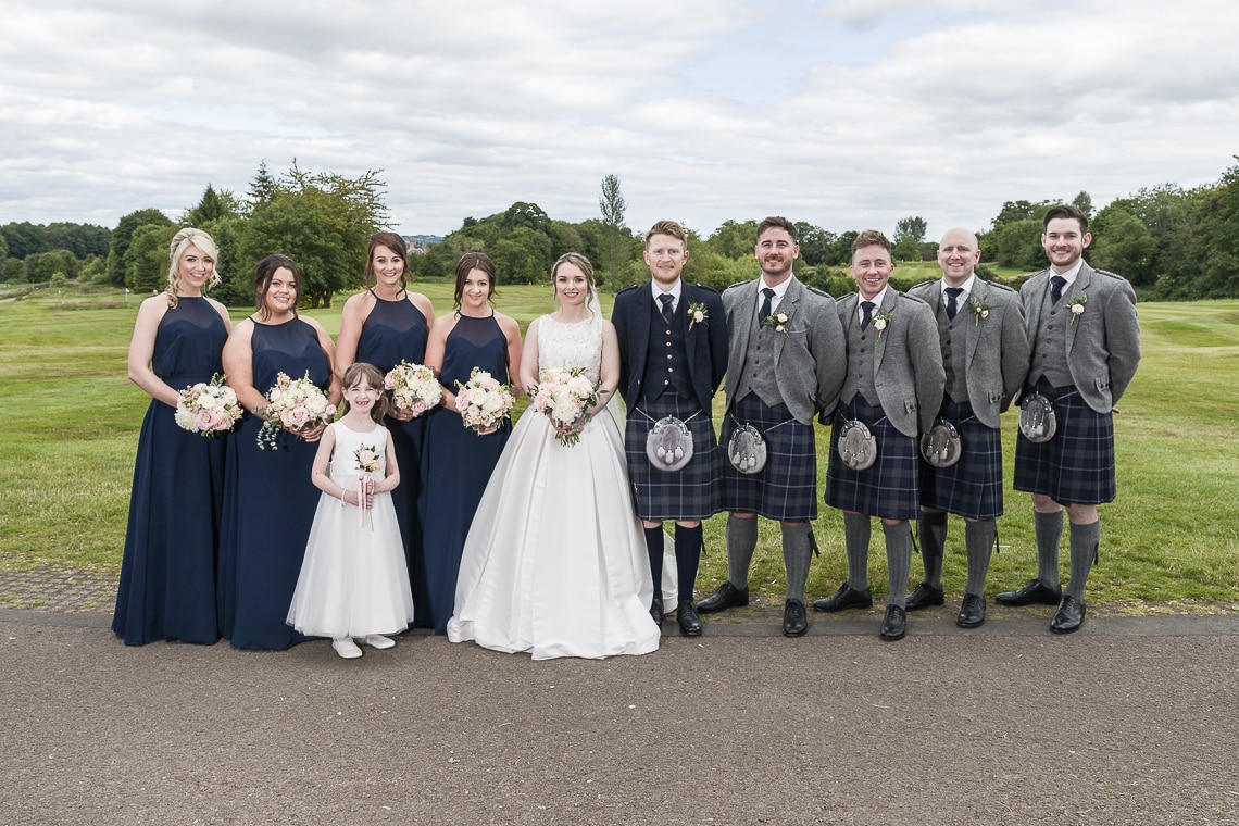 bridal party groom and groomsmen group photo in front of the golf course