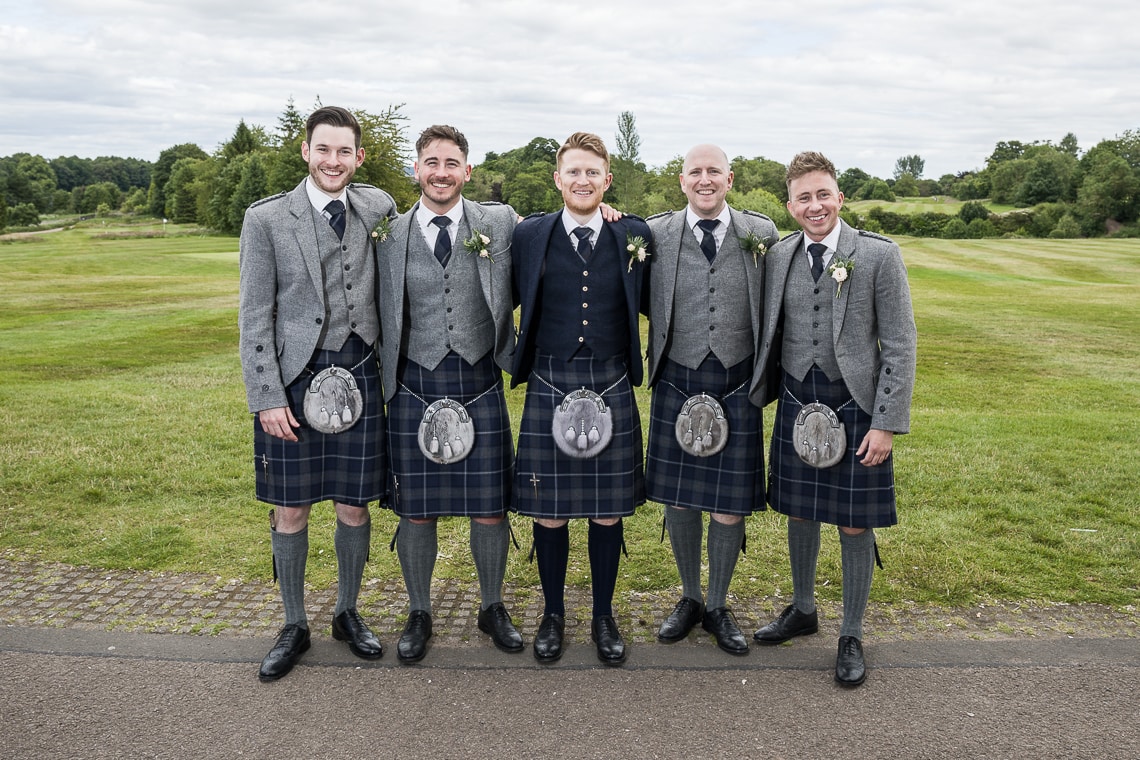 groom and groomsmen group photo in front of the golf course