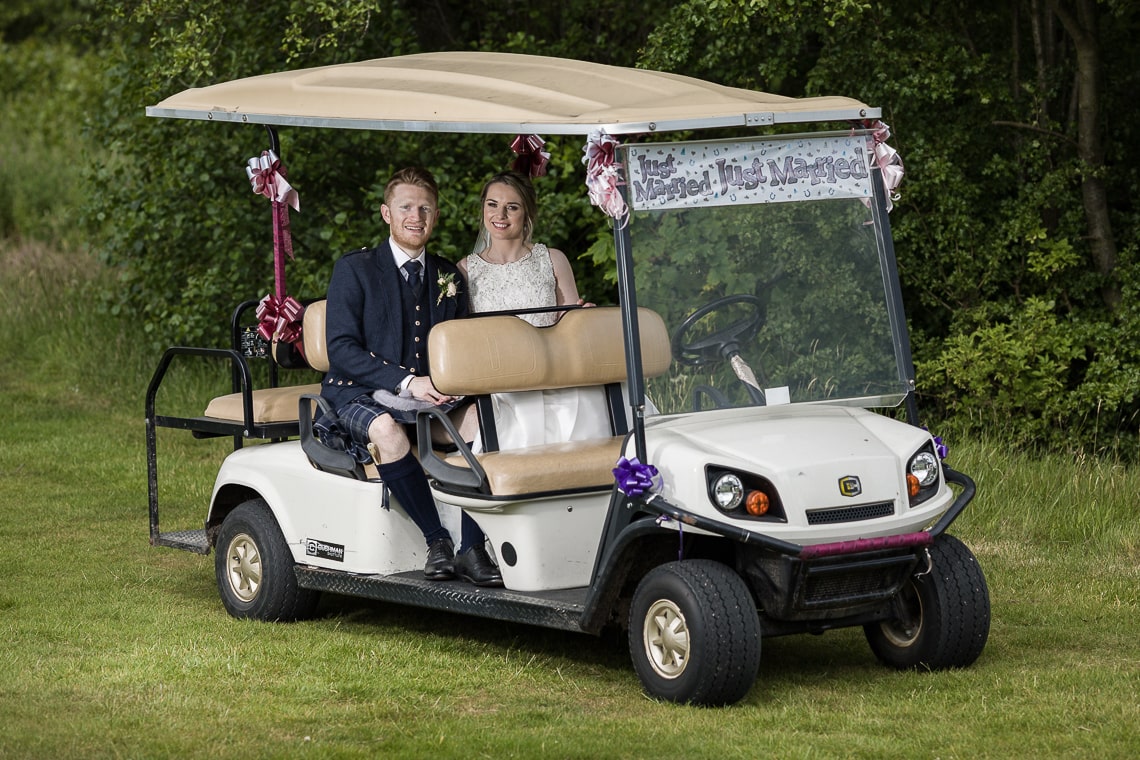 newlyweds sitting in the 'Just Married' golf buggy