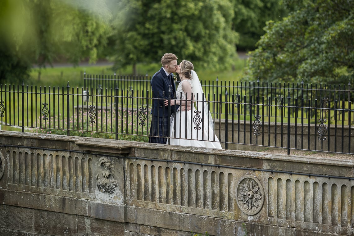 newlyweds standing on the arched bridge at Dalmahoy Hotel