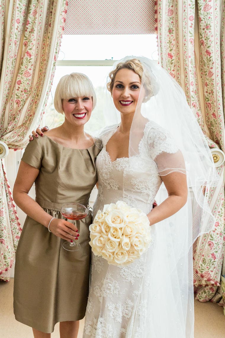 bride and her sister embrace and smile in the Winter bedroom