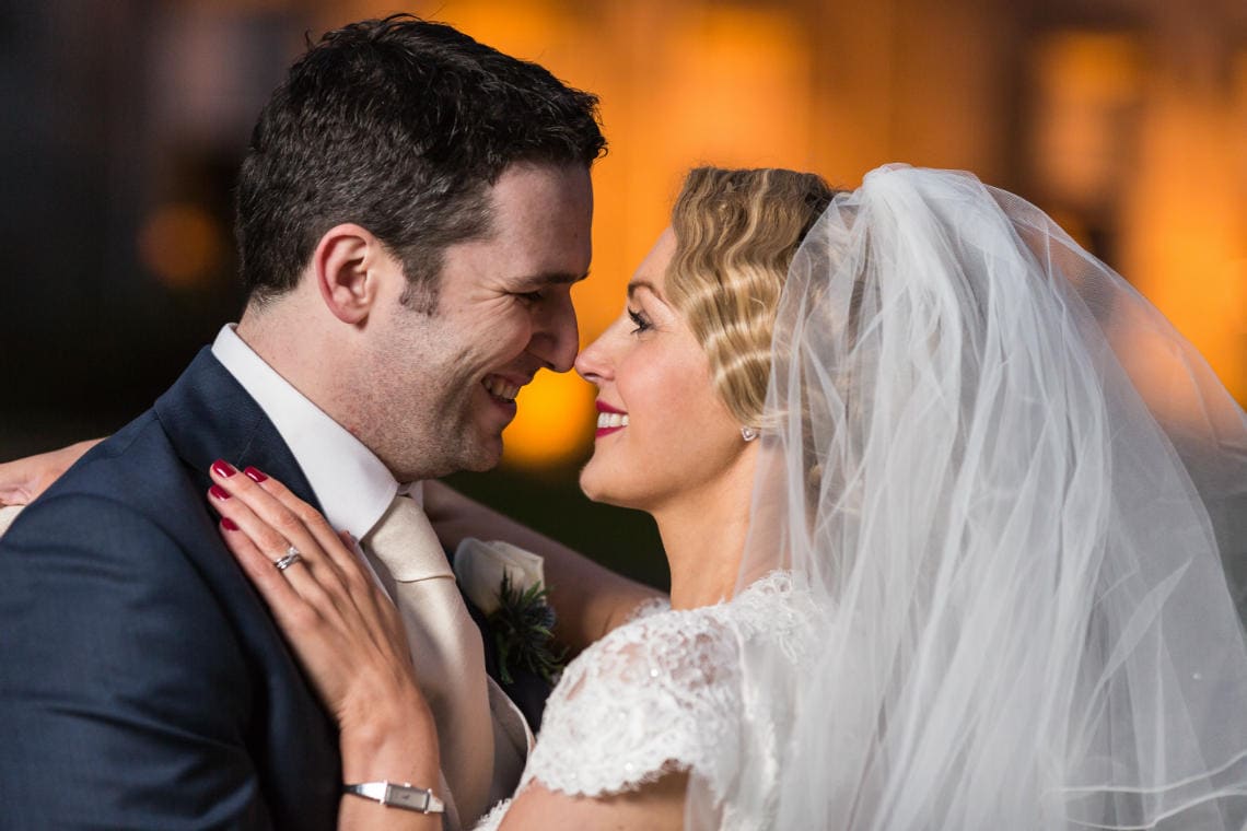 newlyweds embrace at dusk in front of the castle on the lawn with the castle lit up in the background