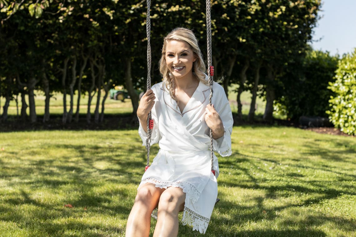 bride pre-ceremony preps on a swing in the garden