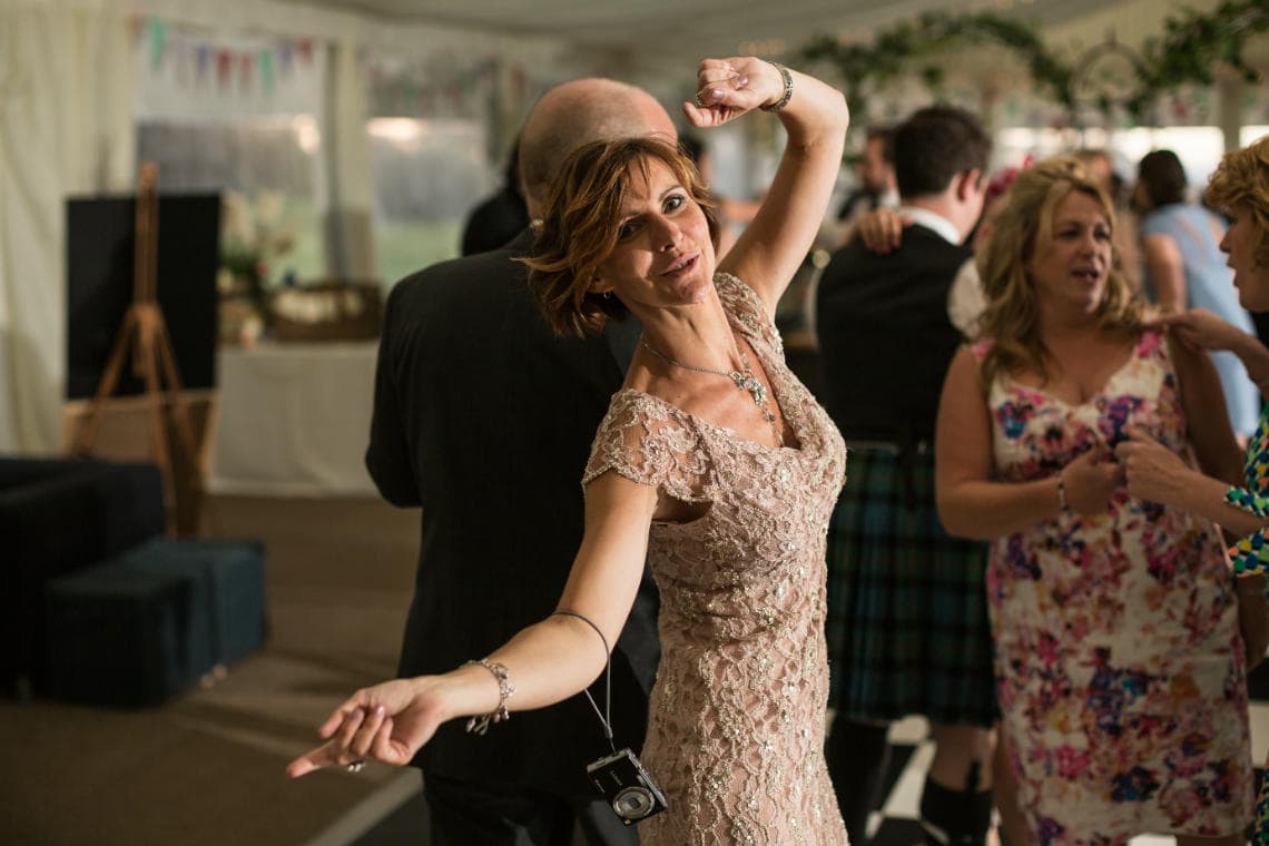 female guest raising her arms as she dances during the evening reception