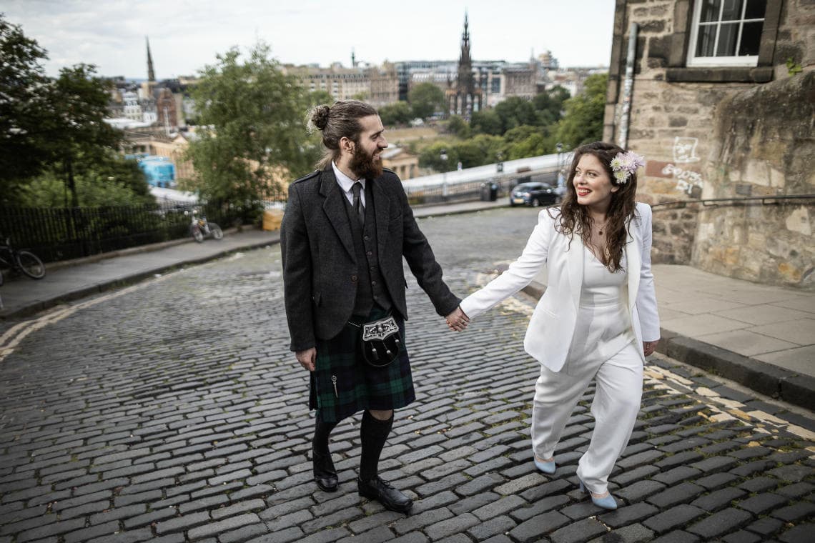 newlyweds holding hands walking on cobbled street