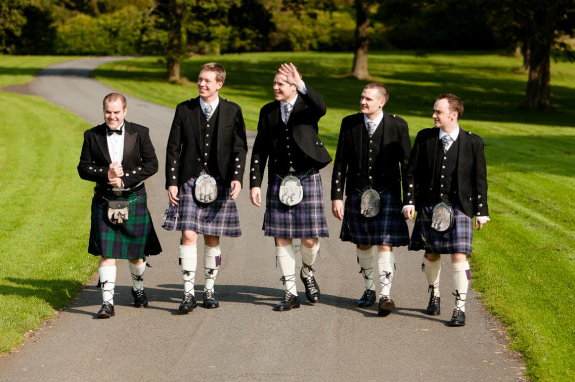 Gardens groom and groomsmen walking along the driveway