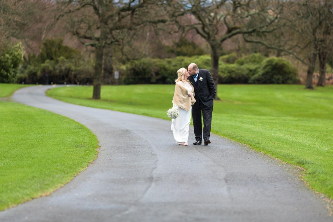 Gardens newlyweds kissing on the driveway