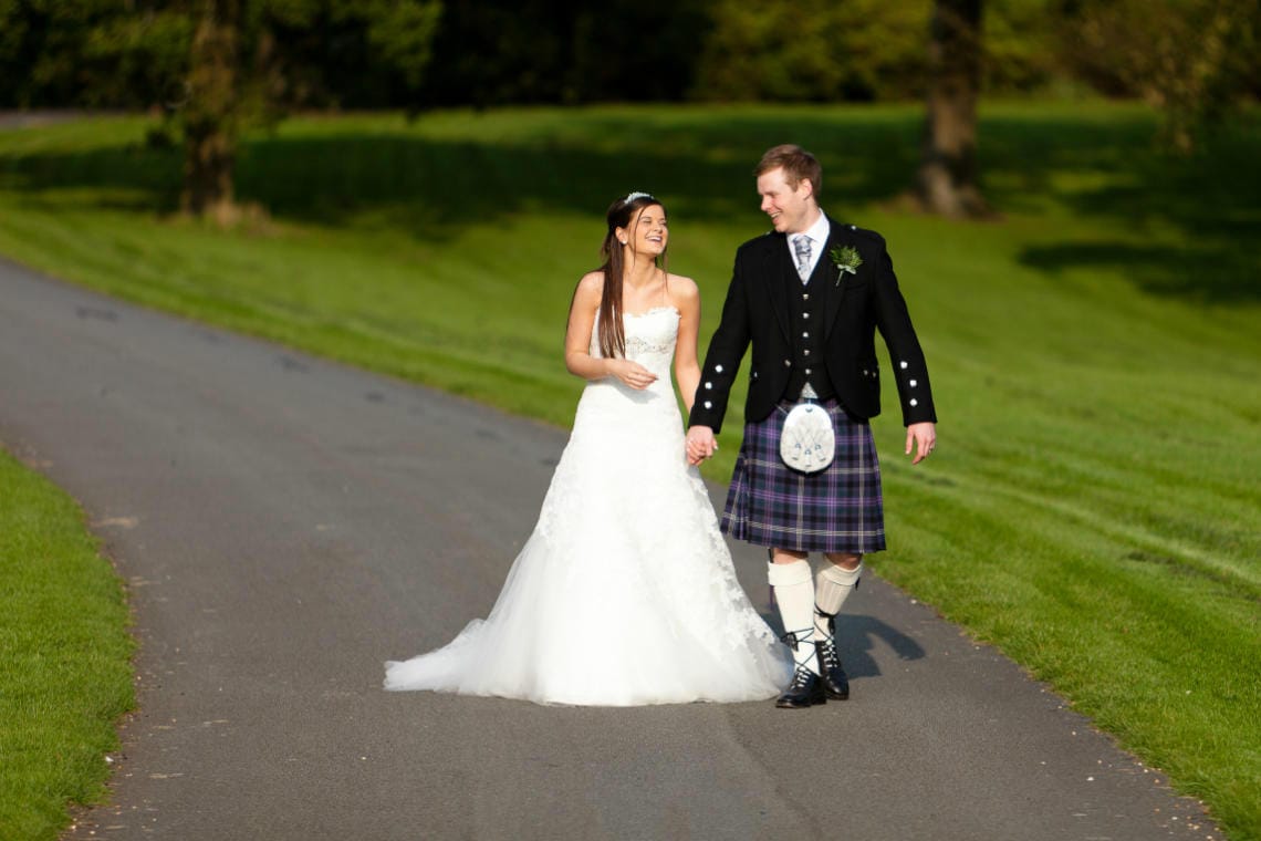 Gardens newlyweds laughing as they walk along the driveway