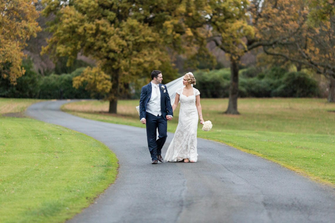Gardens newlyweds walking hand-in-hand along the driveway