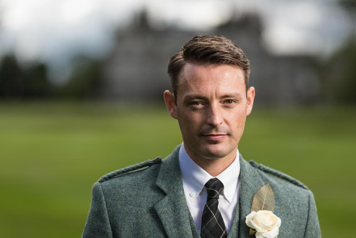 groom portrait with Dalmahoy Hotel blurred in the background