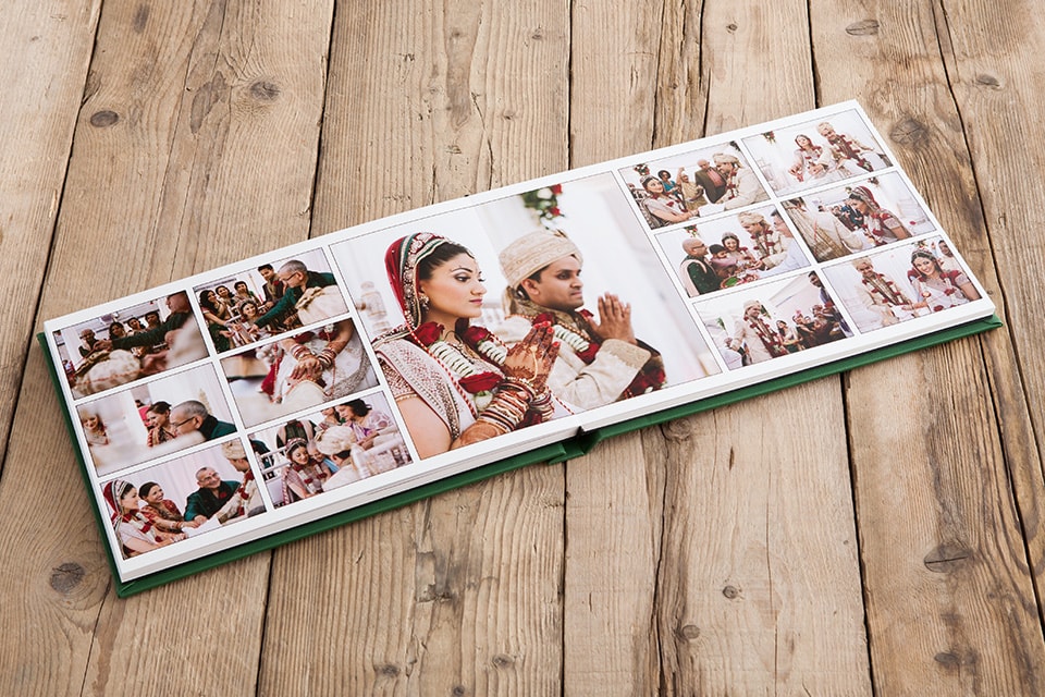 Wedding photo album with pages spread: An open wedding photo album lies on a wooden surface, displaying various images of a couple in traditional attire partaking in cultural wedding rituals.