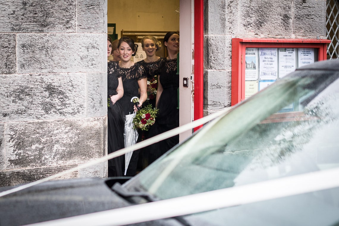 bridesmaids watching the bride arriving in her wedding car