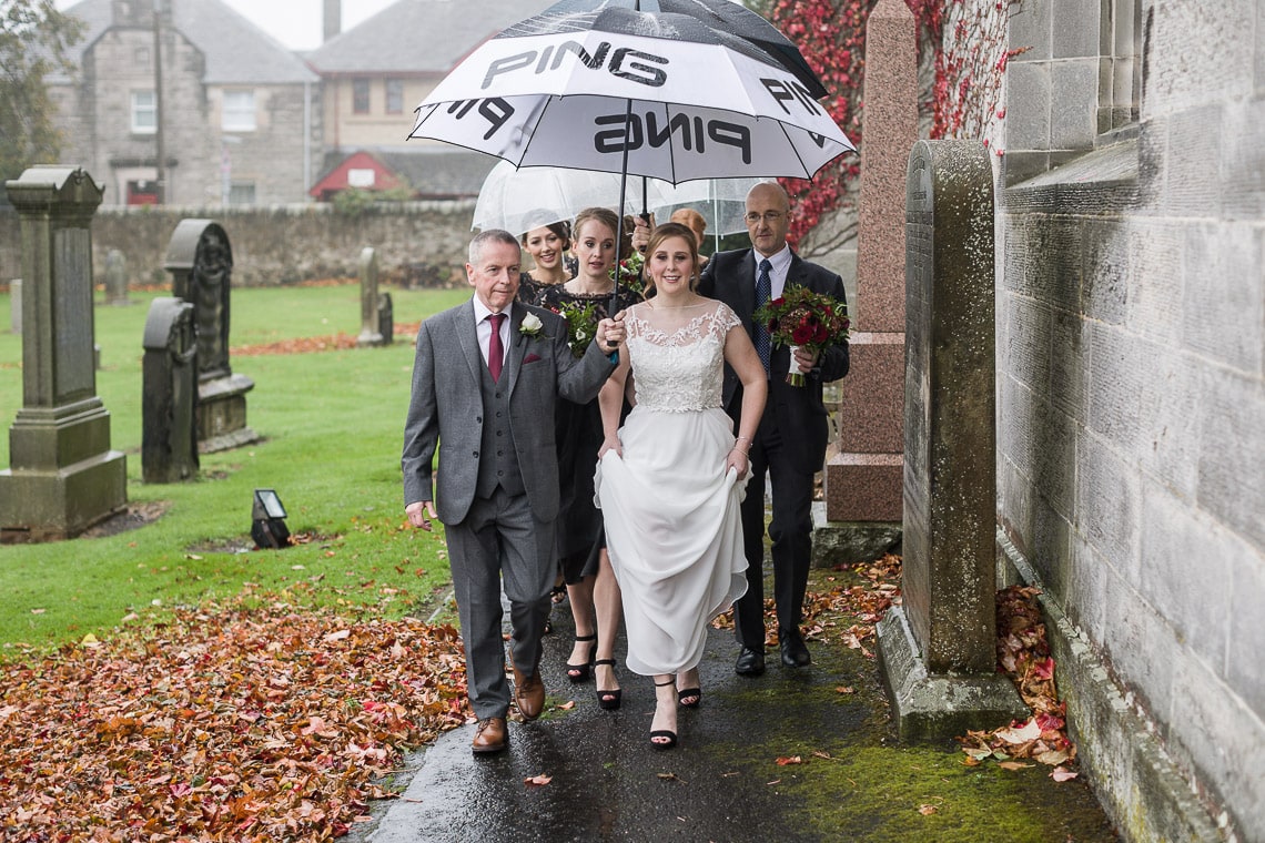 brdial party walking under umbrellas though Liberton Kirk grounds