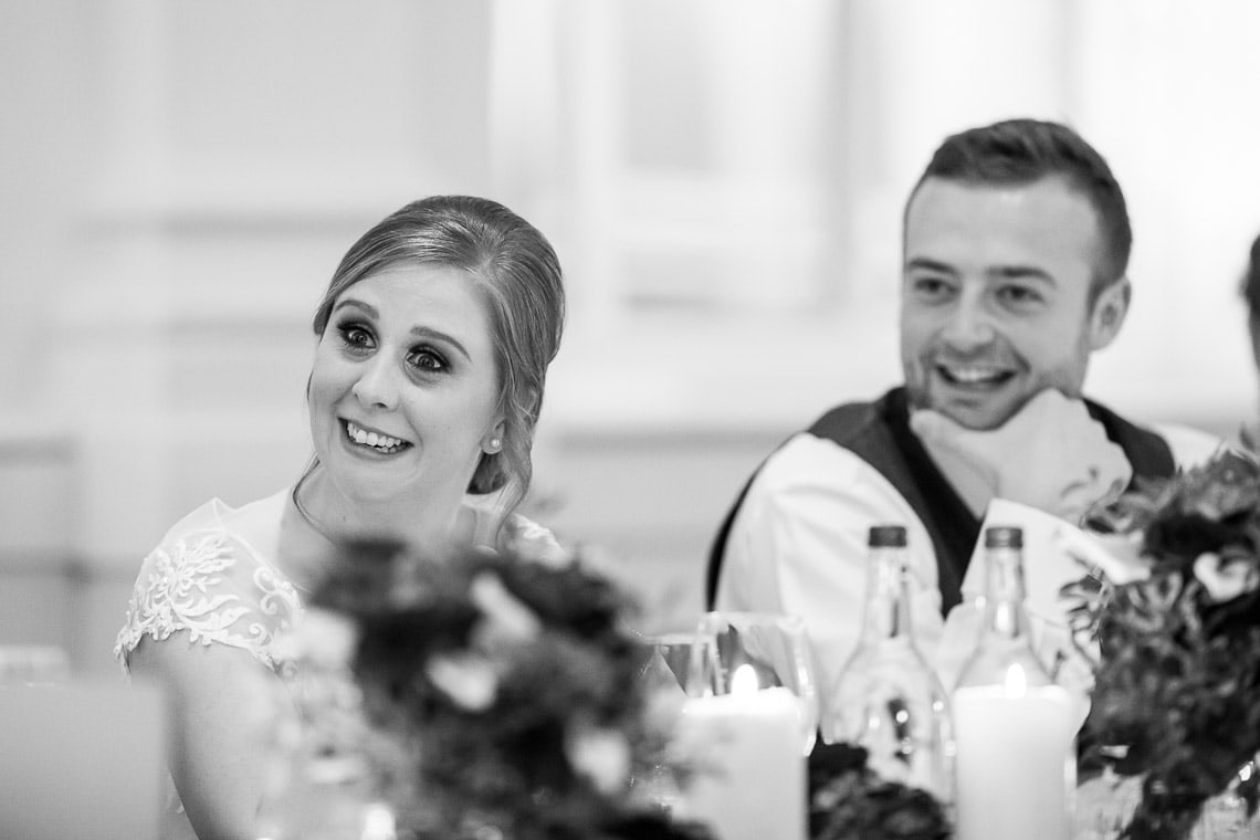 bride and groom watching father of the bride speech in the King's Hall