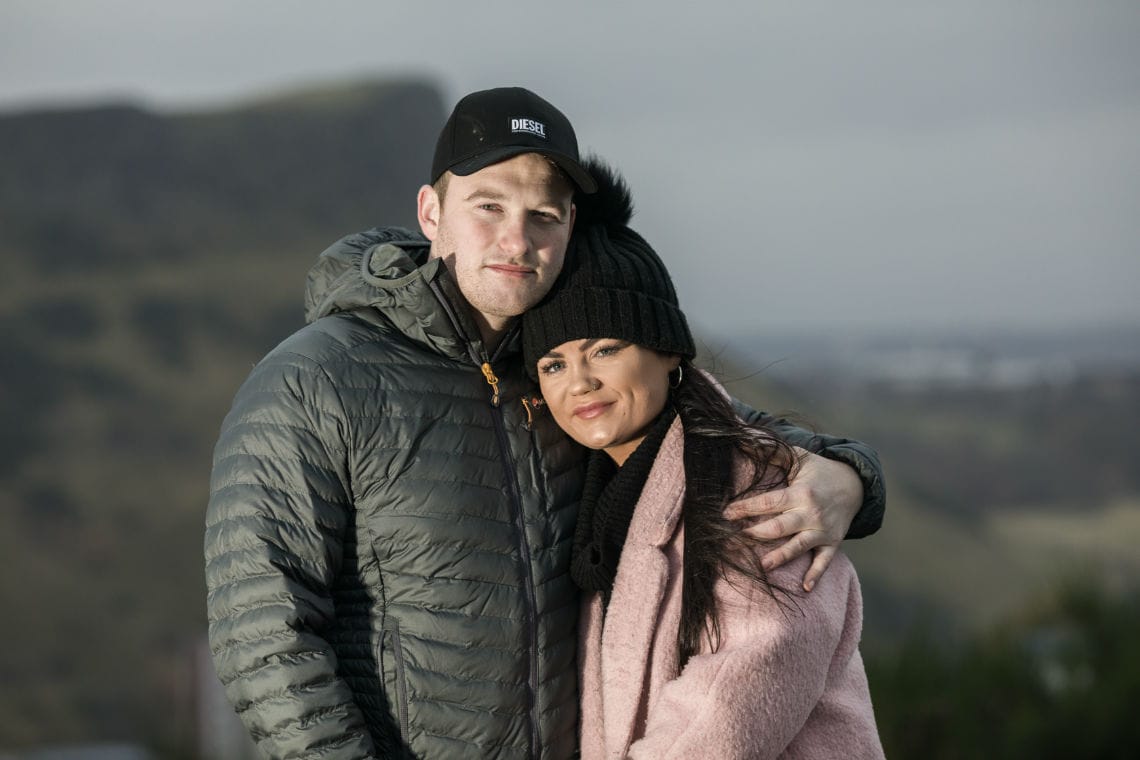 couple embrace with Salisbury Crags in the background