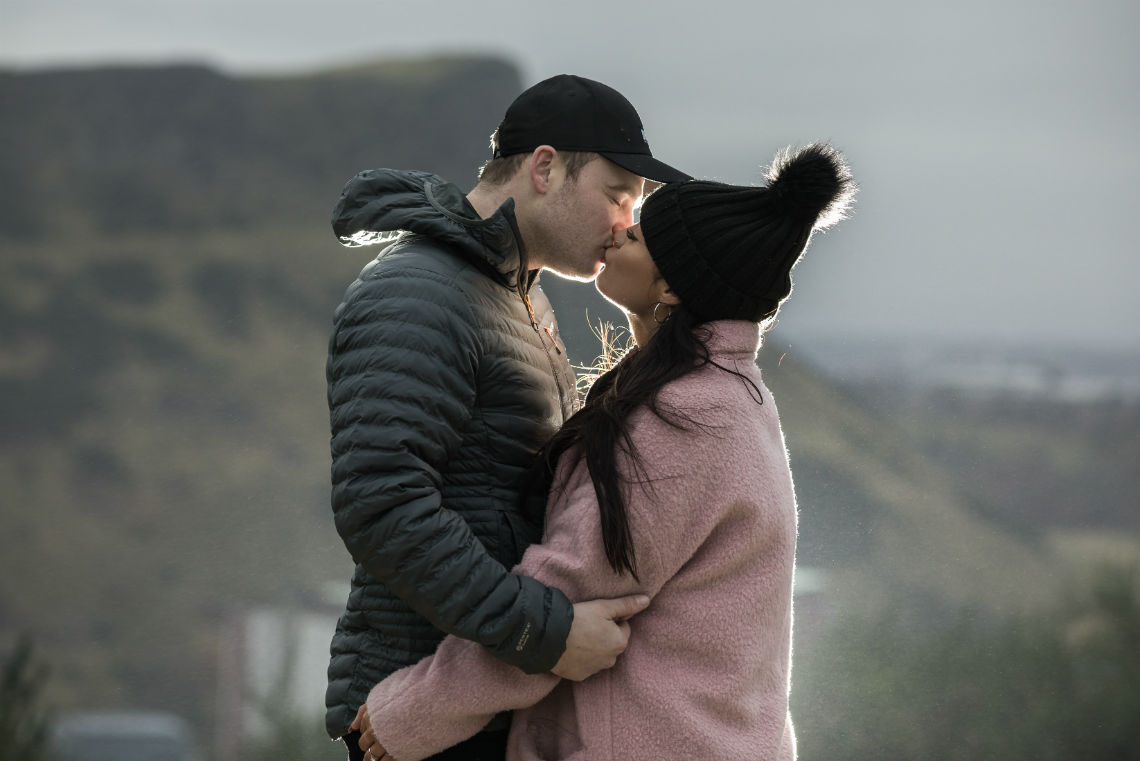 couple kiss with Salisbury Crags in the background