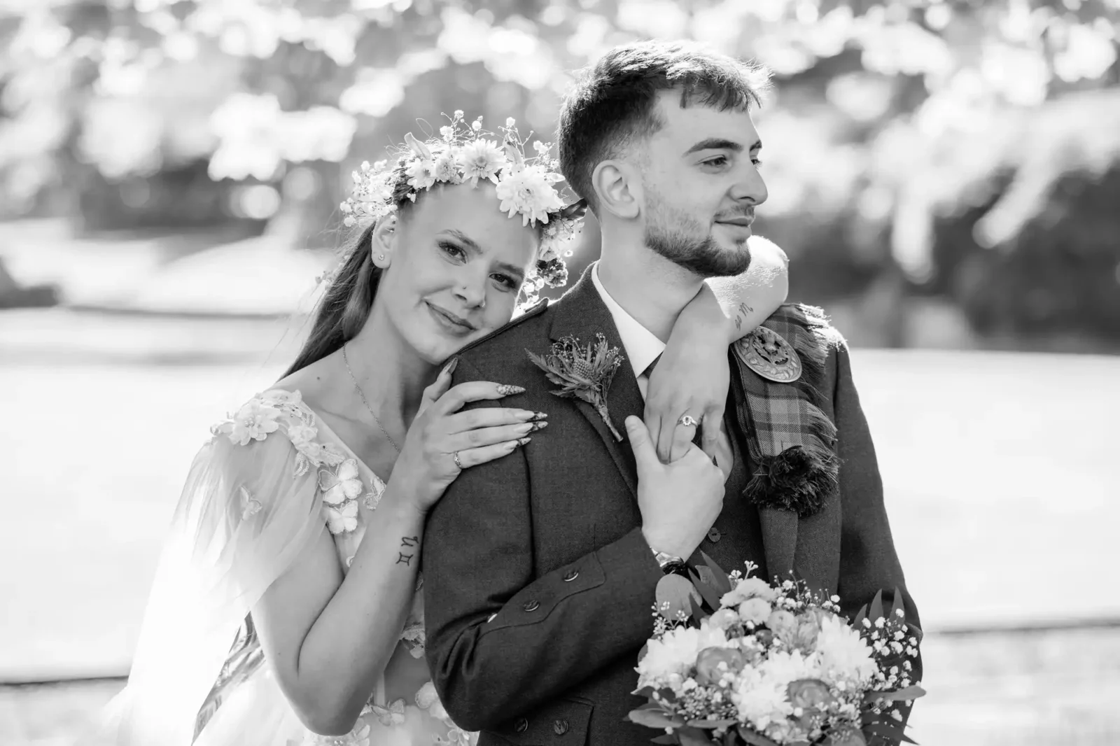 Edinburgh elopement guide for couples captured by Edinburgh wedding photographer. Prestonfield House wedding. A bride rests her head on the groom’s shoulder as they pose outdoors; she smiles gently while he looks ahead, holding a bouquet.