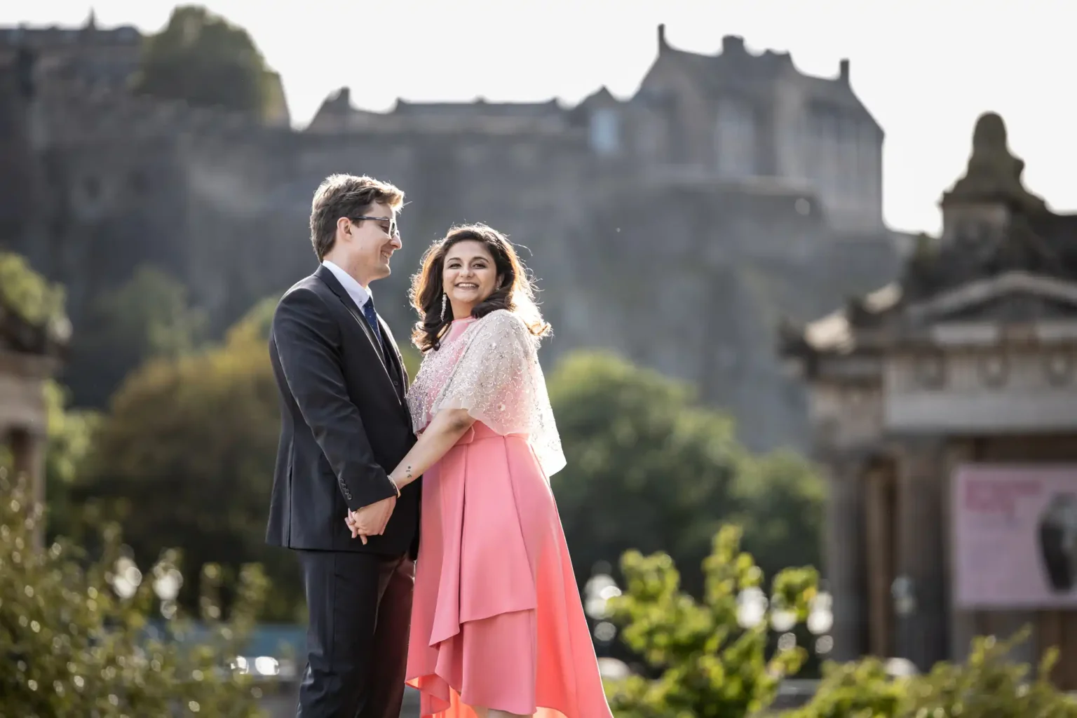 Edinburgh City Chambers and The Scotsman Hotel wedding photographer: A man and woman holding hands, smiling at each other, standing outdoors with a historic building in the background.
