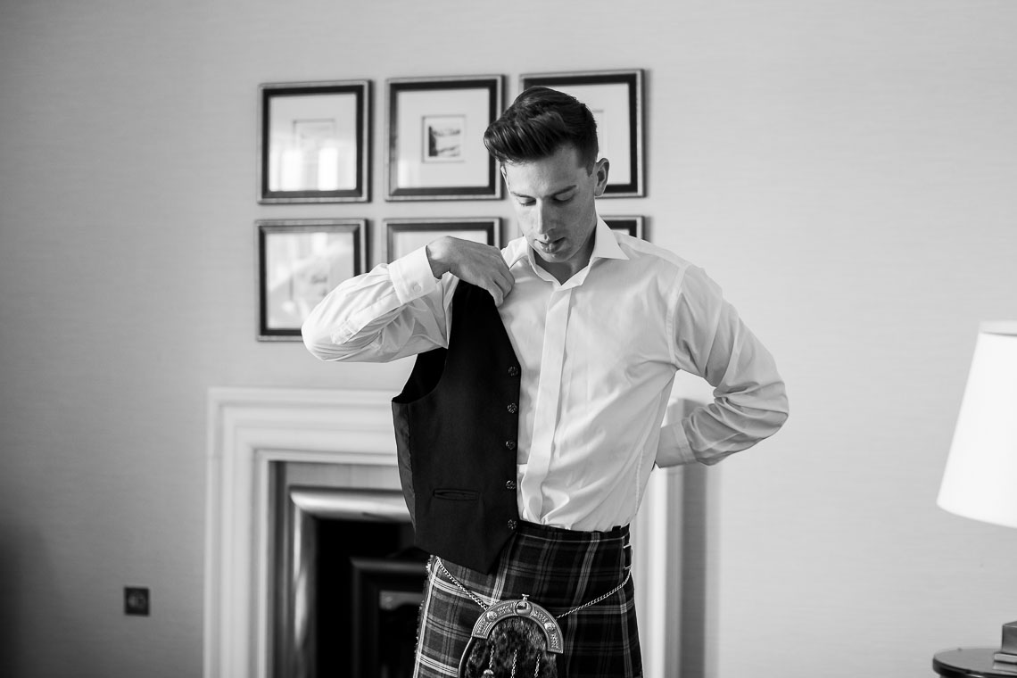 groomsman putting on a waistcoat