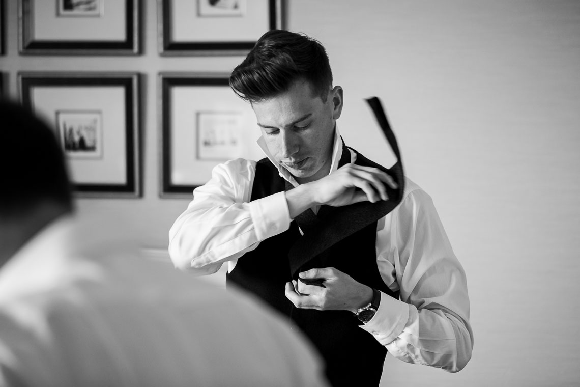 groomsman tying a tie