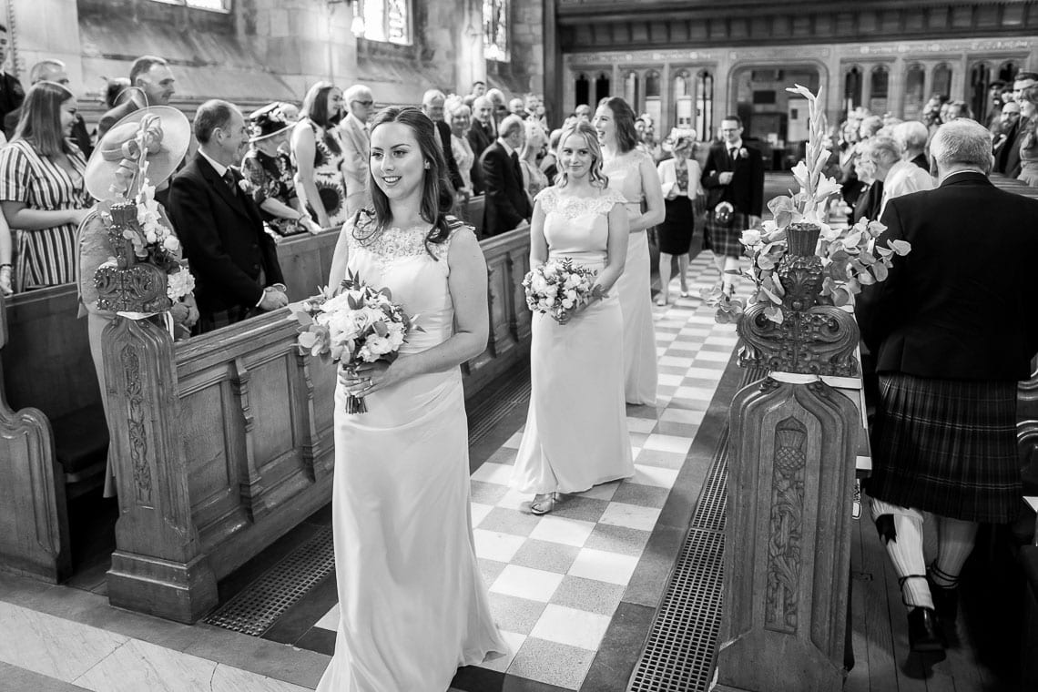 groom watches bridesmaids walking up the aisle