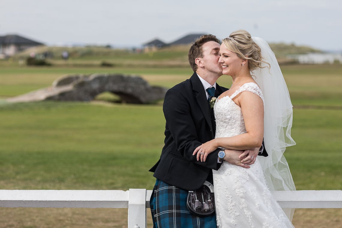 newlyweds embrace with Swilken Bridge in the background