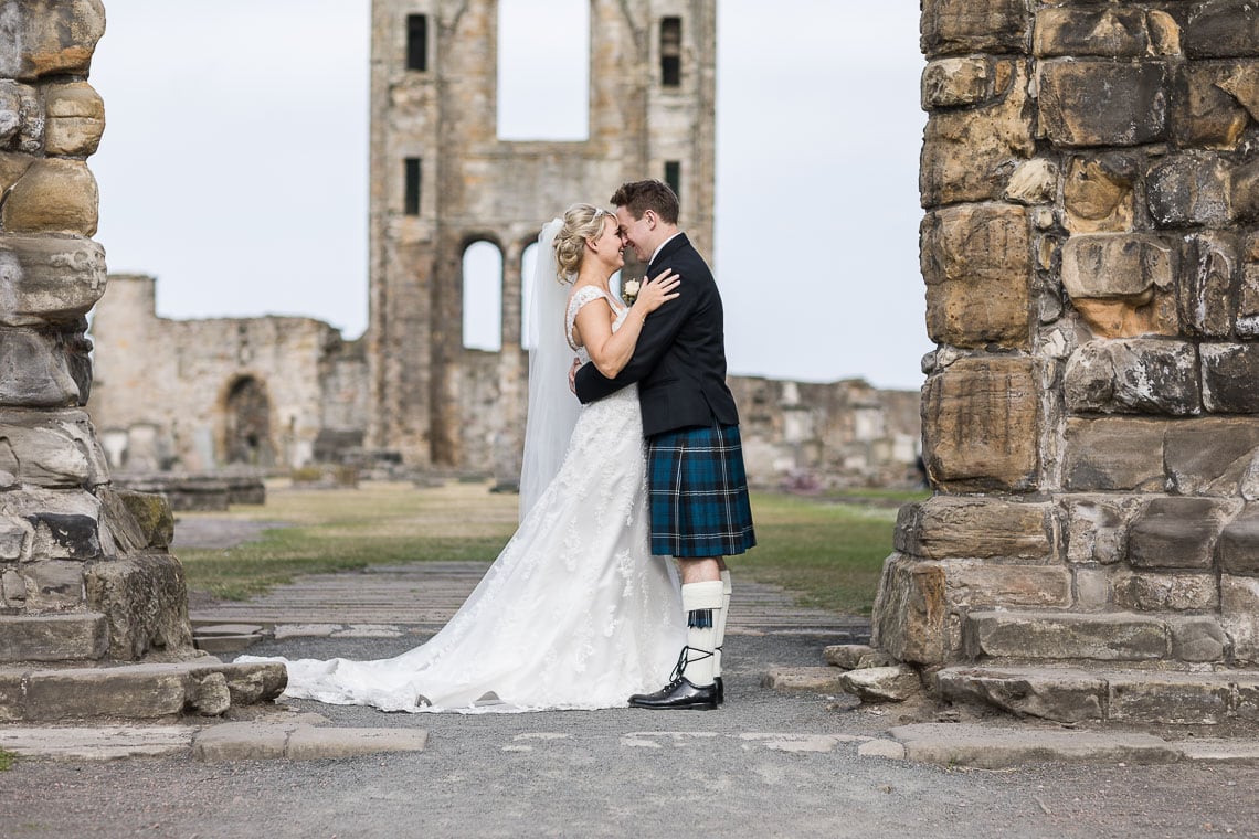 newlyweds embrace under the arch at St Andrew's Cathedral