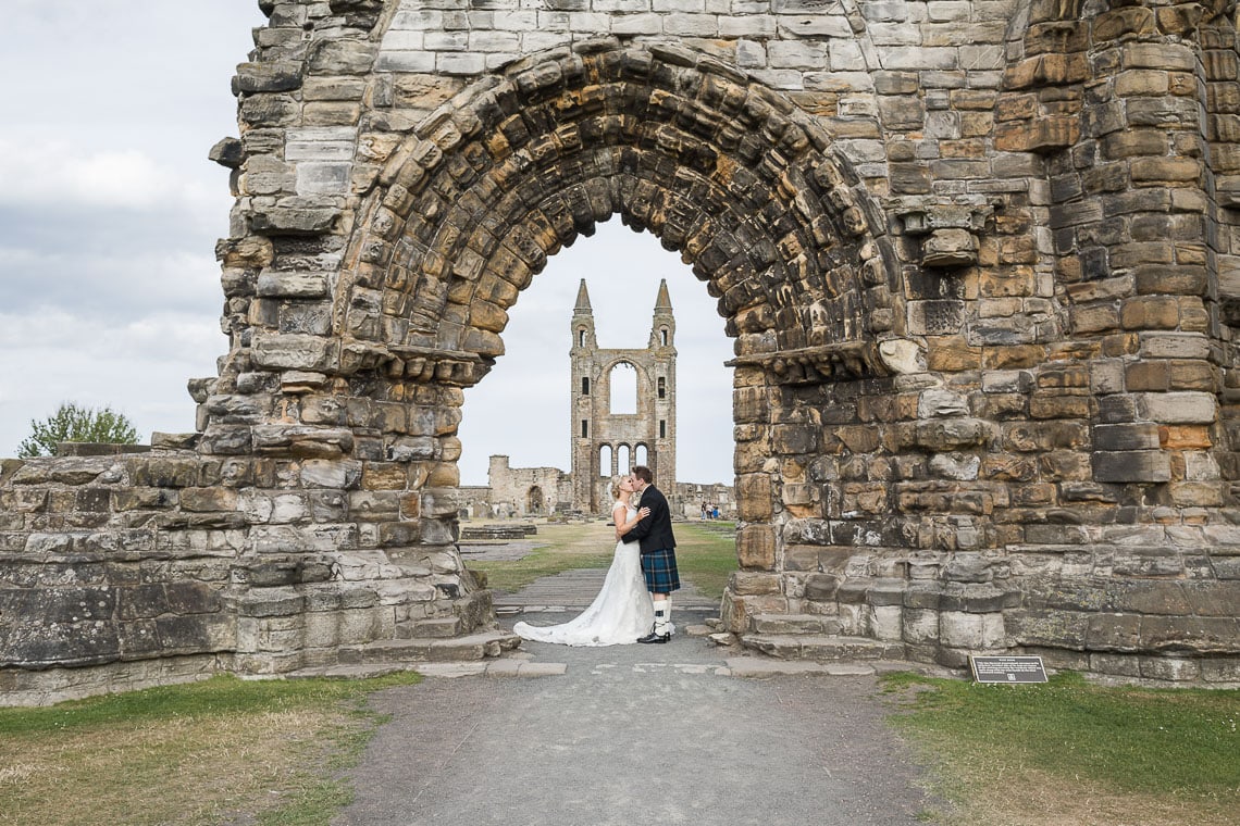 newlyweds embrace under the arch at St Andrew's Cathedral