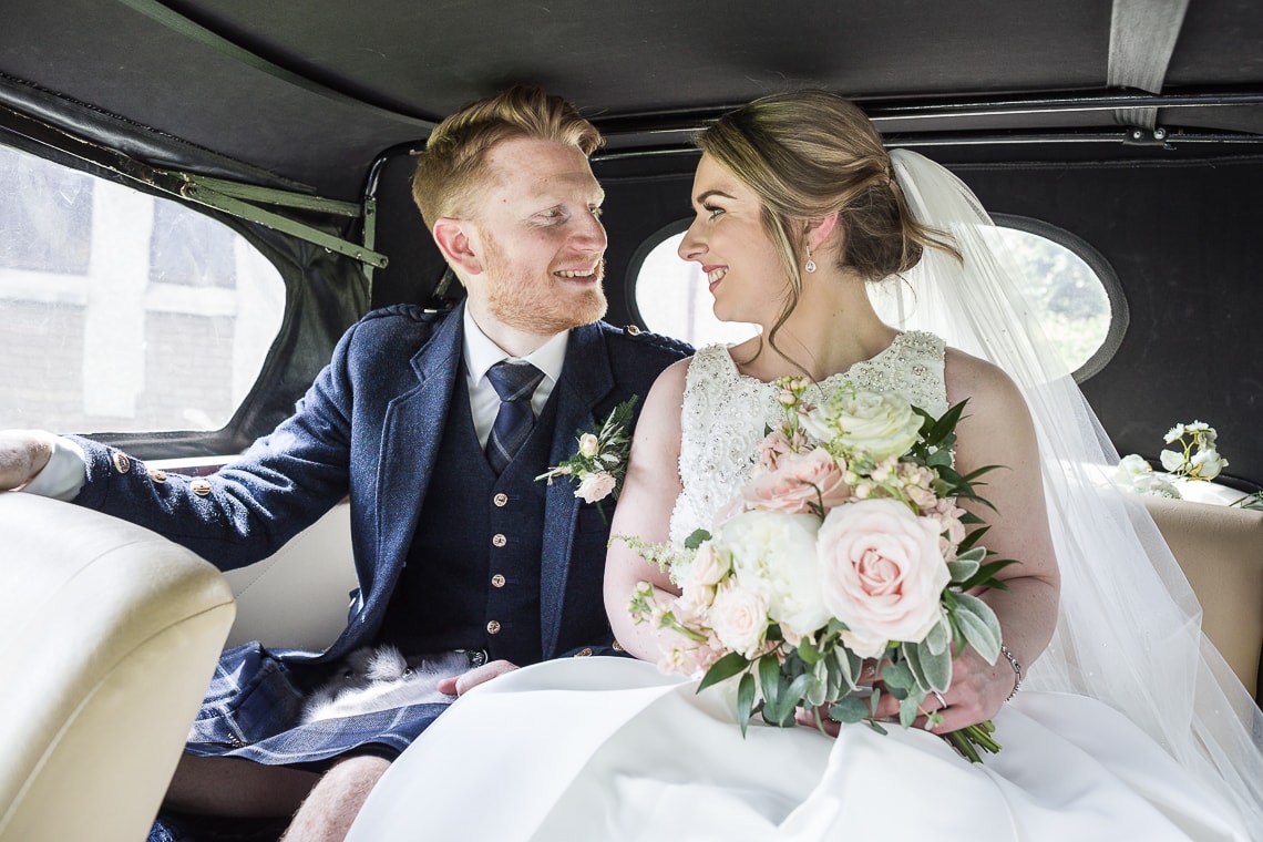 St. Anthony's Polmont wedding photographer: newlyweds sitting in the back of a Beauford car