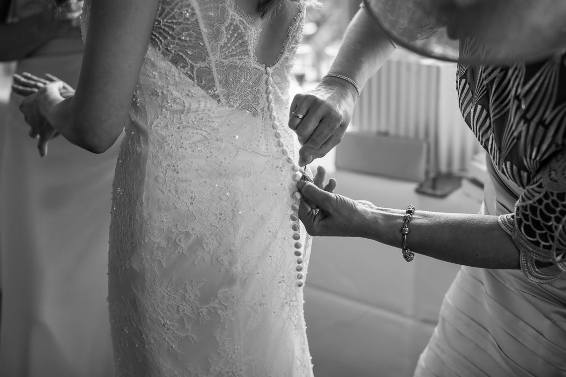 bridesmaid helping button up the bride's dress in the Forthview Suite