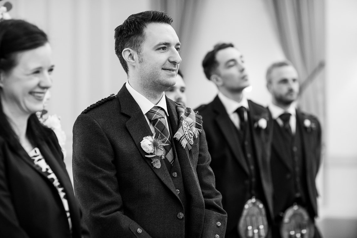 groom watchiung the arrival of the bride in the Kings Hall