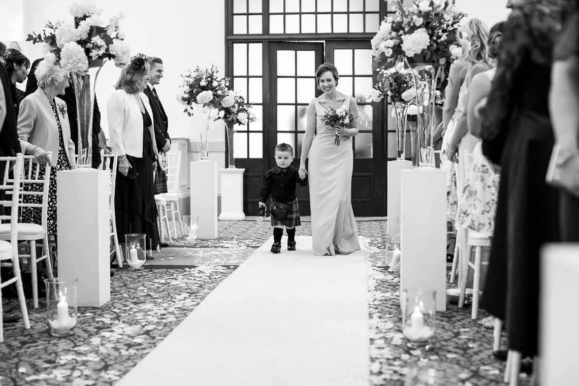 bridesmaid and page boy walking up the aisle in the Kings Hall`