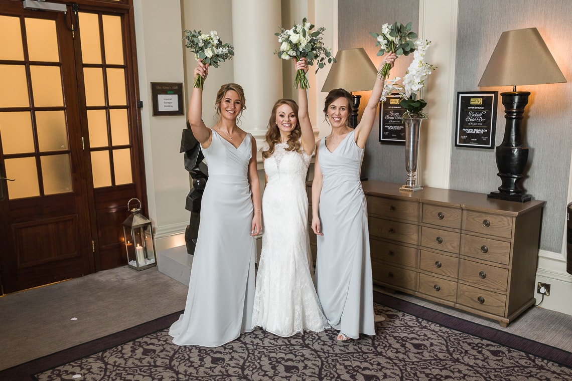 bride and bridesmaid punching the air outside the King's Hall